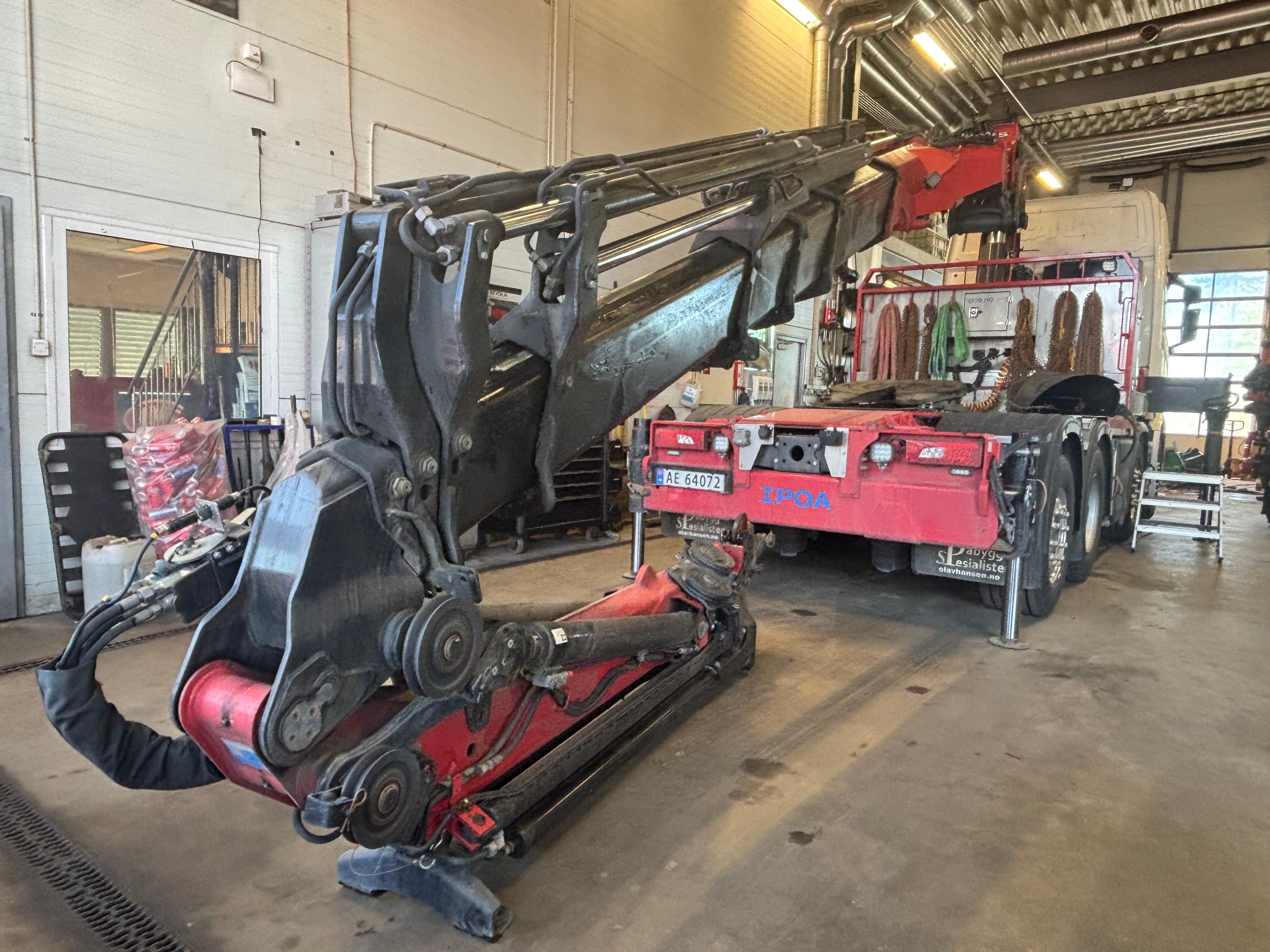 Rød og sort lastebil med en stor hydraulisk kranmontering